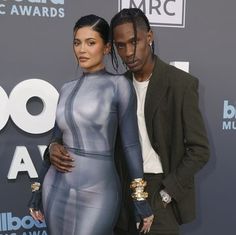 two people standing next to each other on a red carpet