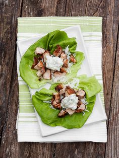 two lettuce wraps filled with meat and cheese on top of a white plate