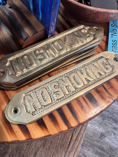 two metal nameplates sitting on top of a wooden table next to blue vases