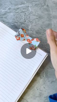 someone is holding an origami butterfly on top of a notebook