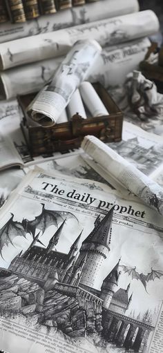 newspapers and other items on a table with paper rolls in the foreground, including an image of hogwart's castle