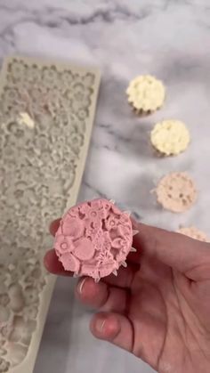 a person is holding a piece of pink and white lace in front of some doily