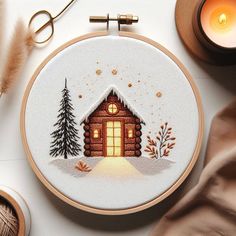 a cross stitch christmas scene with a small cabin in the snow