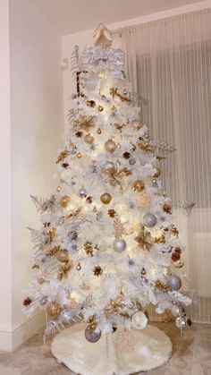 a white christmas tree with gold and silver ornaments