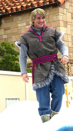 a man dressed up in costume standing on top of a snow covered ground next to a building