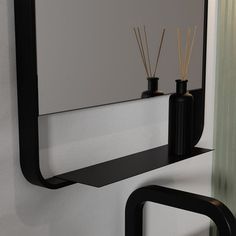 a mirror and some black vases on a wall