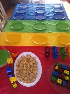 a table topped with plates and bowls filled with food next to legos on top of each other