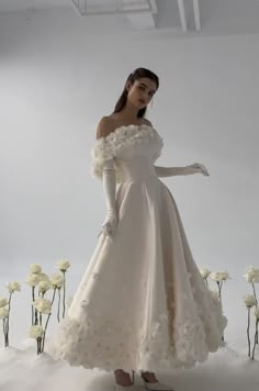 a woman in a white dress standing next to flowers