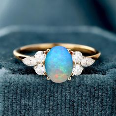 an opal and diamond ring sits on top of a blanket