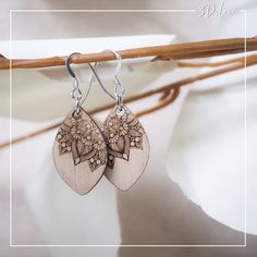 wooden earrings with intricate designs hang from a twig