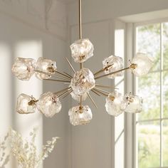 a chandelier hanging from the ceiling in a room with white walls and windows