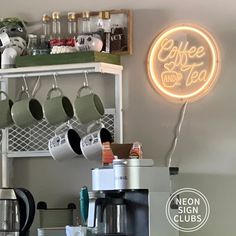 a coffee shop with cups and mugs on the shelf next to a neon sign