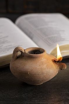 an open book with a lit candle in front of it on a table royalty images