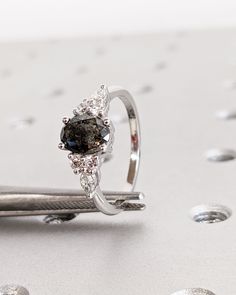 a diamond ring sitting on top of a table next to a pair of tongs