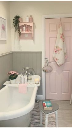 a white bath tub sitting in a bathroom next to a pink door with flowers on it