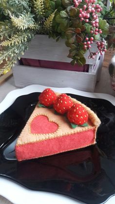 a piece of cake with strawberries on top sits on a plate next to flowers