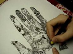 a person drawing on paper with colored pencils