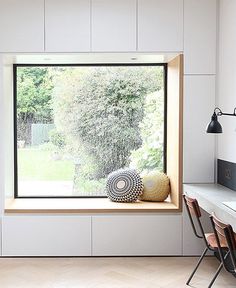 an open window in a white room with two chairs and a table next to it