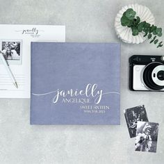 personalized wedding guest book with photo and pen on table next to camera, flowers