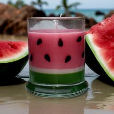 a watermelon candle sitting on top of a table next to two slices of watermelon