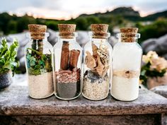 three glass bottles filled with different types of spices and herbs sitting on top of a stone slab