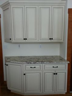 an empty kitchen with white cabinets and granite counter tops