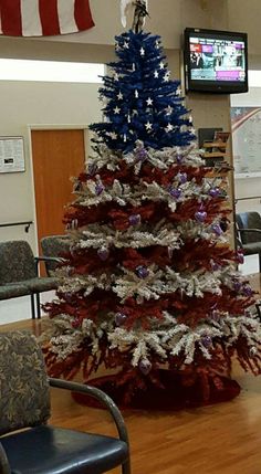 a decorated christmas tree in an office with american flags on the wall and chairs around it