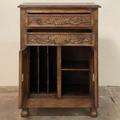 an old wooden cabinet with two doors and drawers on one side, in front of a white wall