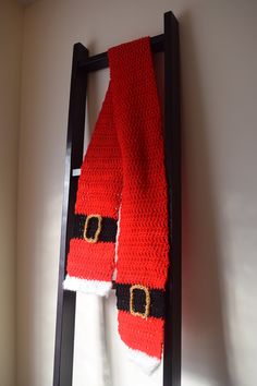 a scarf hanging on a ladder with santa's hat and belt attached to it