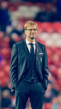 a man in a suit and tie standing on the sidelines at a soccer game