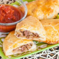 two pastries on a green plate with sauce and ketchup in the background