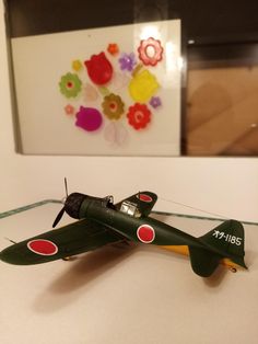 an old model airplane is on display in a museum case with a painting behind it