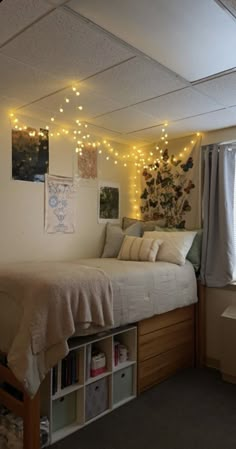 a room with a bed, bookshelf and lights on the wall above it