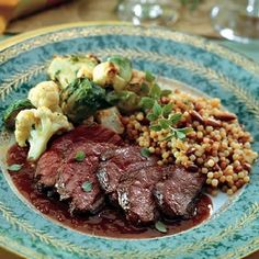 a blue and gold plate topped with meat, vegetables and corn on top of it