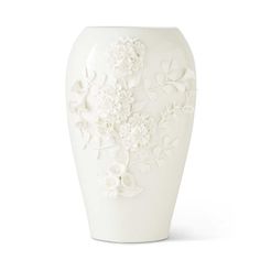 a white vase with flowers and leaves on it