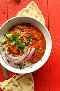 a white bowl filled with food next to pita bread