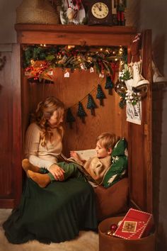 a woman and child sitting on a chair in front of a christmas tree