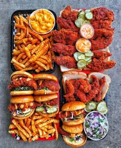 several trays filled with different types of food including chicken, fries and coleslaw