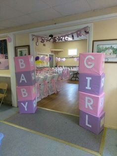 a baby shower is set up with pink and purple blocks on the floor, along with white tablecloths