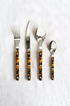 three forks, two spoons and one knife on a white tablecloth with animal print