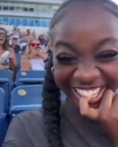 a woman with braids smiling and holding her hand to her face in front of an audience