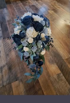 a bouquet of blue and white flowers sitting on top of a wooden floor in a room