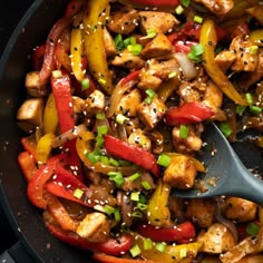 a skillet filled with chicken, peppers and sesame seeds