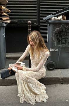 a woman sitting on the ground next to trash cans