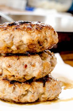 three hamburger patties stacked on top of each other with sauce drizzled over them