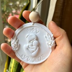 a hand holding a white ornament with a baby's face on it