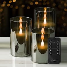 three candles are lit in front of a remote control