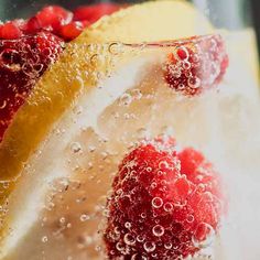 raspberries and lemon wedges in water with bubbles on the glass, closeup