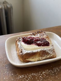 a piece of bread with powdered sugar and jelly on it sitting on a plate