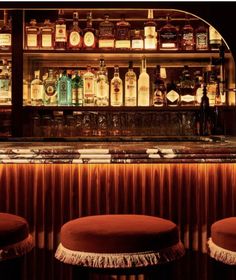 a bar with stools and bottles behind it